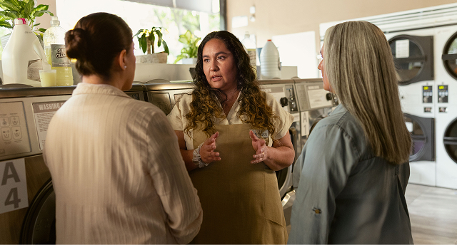 Imagen de mujer hablando con dos personas en lavandería